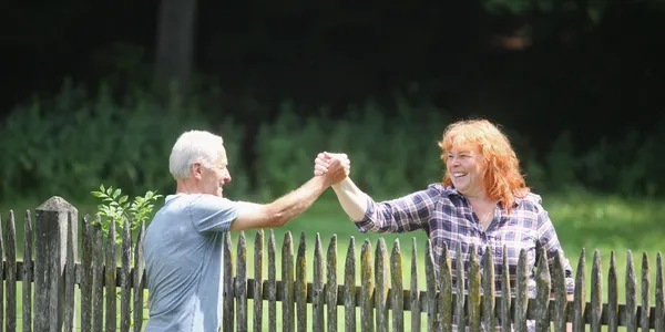 Neighbors shaking hands across a property fence